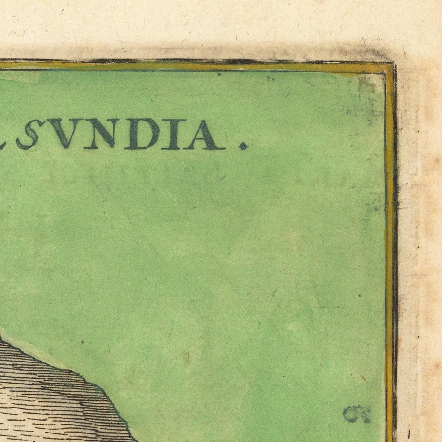Close-up of an antique map or print corner with a pale green field, dark printed text reading 'SVDIA', a thin yellow border line, and aged beige paper around it.